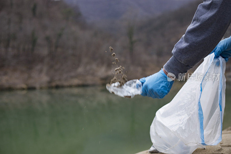 一名年轻人在河边捡塑料瓶