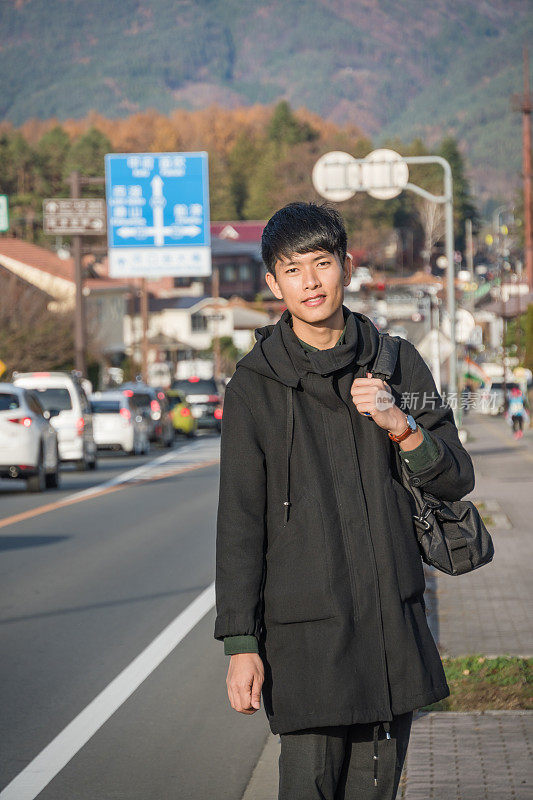 年轻的亚洲男子和日本朋友寻找旅游地点使用手机和花时间在亚洲旅行