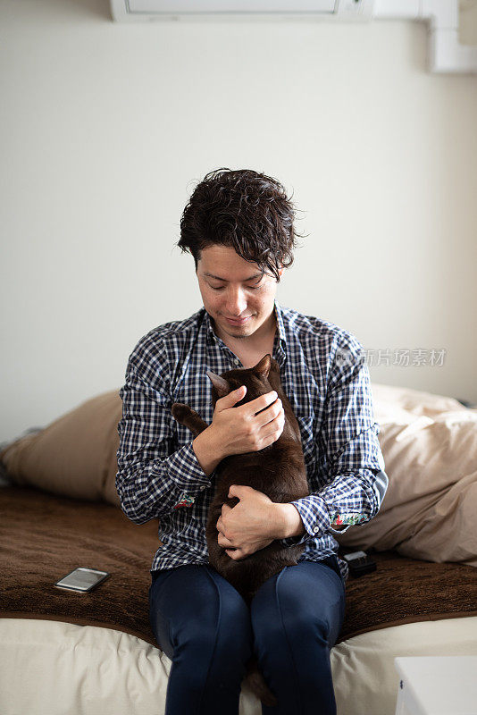 一个男人在卧室抱着一只猫