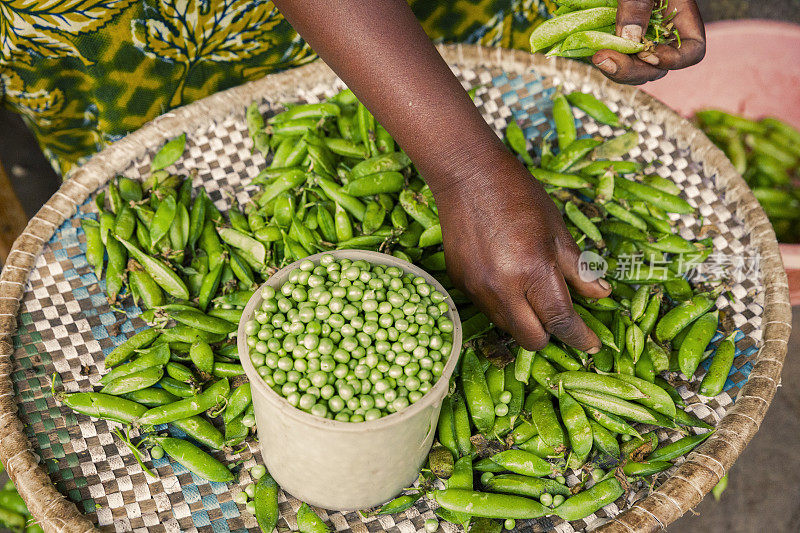 卢旺达，一名妇女在市场上用手剥豌豆