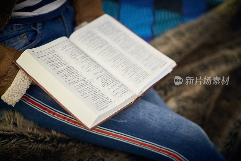 穿着牛仔裤的年轻人膝上放着一本圣经