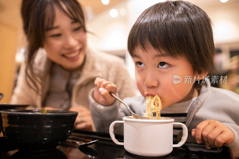 小男孩在美食广场做鬼脸吃拉面