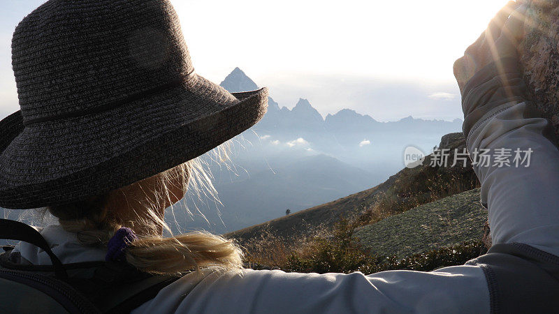 日出时分，女徒步旅行者在高山休息