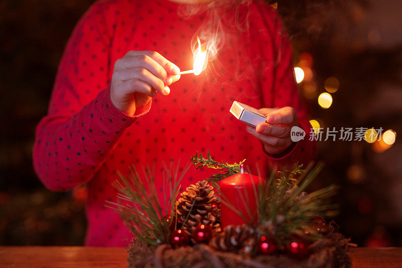 女孩正在点燃降临节花环上的蜡烛