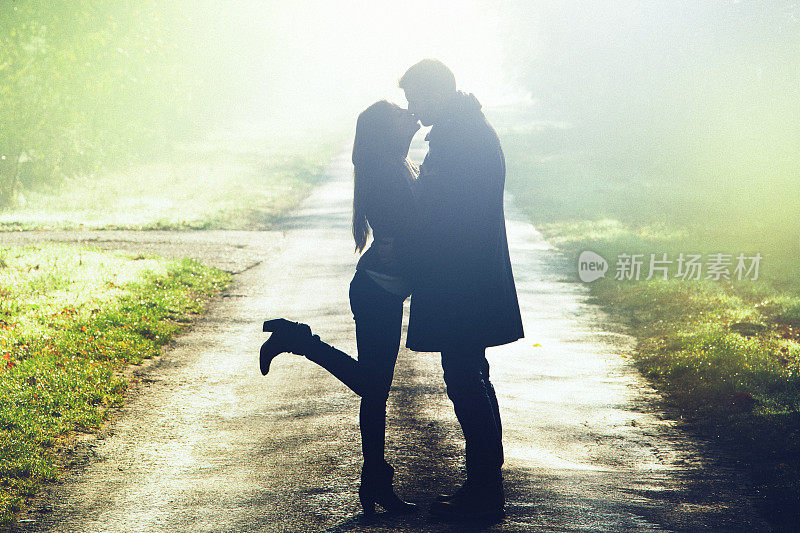 一对年轻的情侣在秋天的阳光下接吻