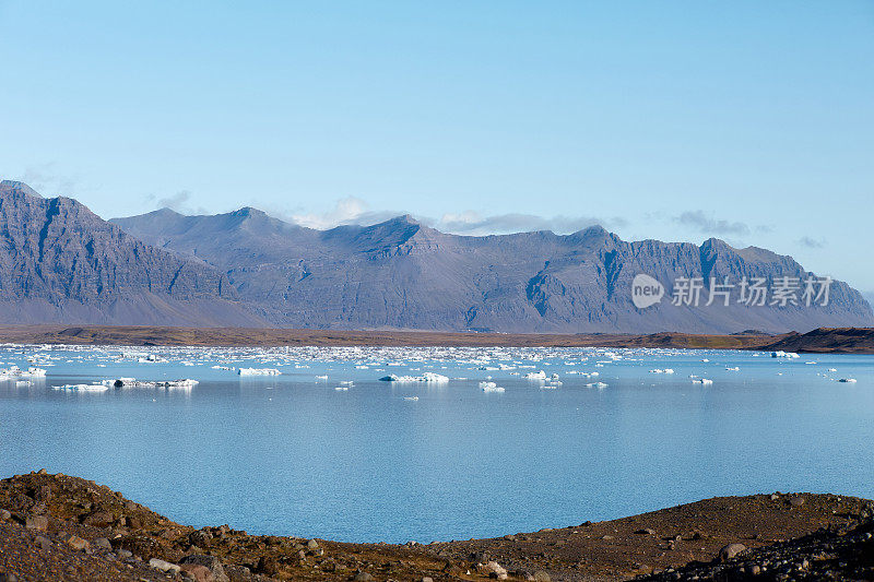 美丽的风景，清澈的湖与冰块闪闪发光的阳光下，高山背景。Jokulsarlon泻湖、冰岛