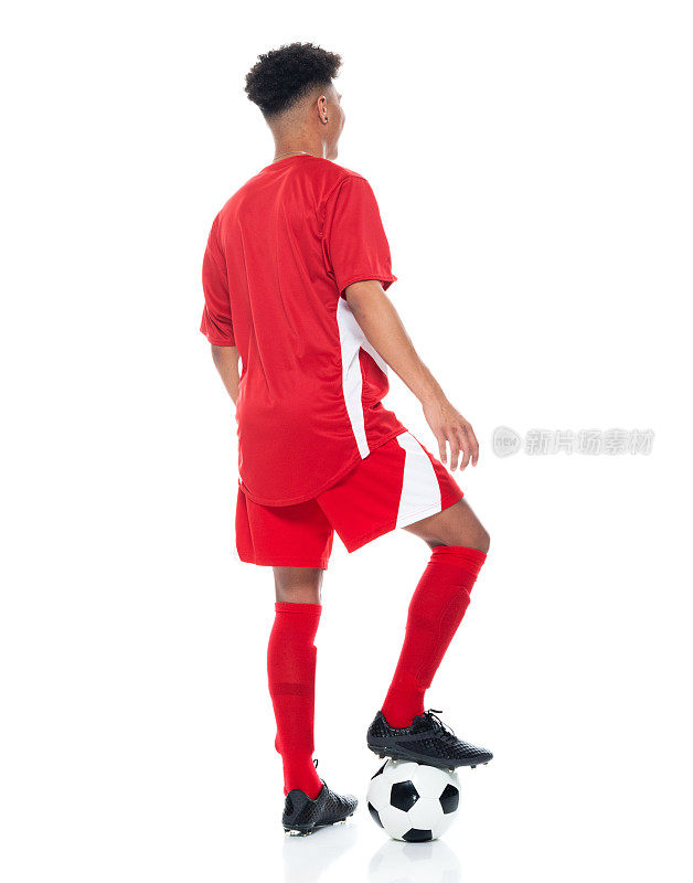 非洲裔少年运动员穿着足球制服站在白色背景前，拿着足球玩足球运动和使用运动球