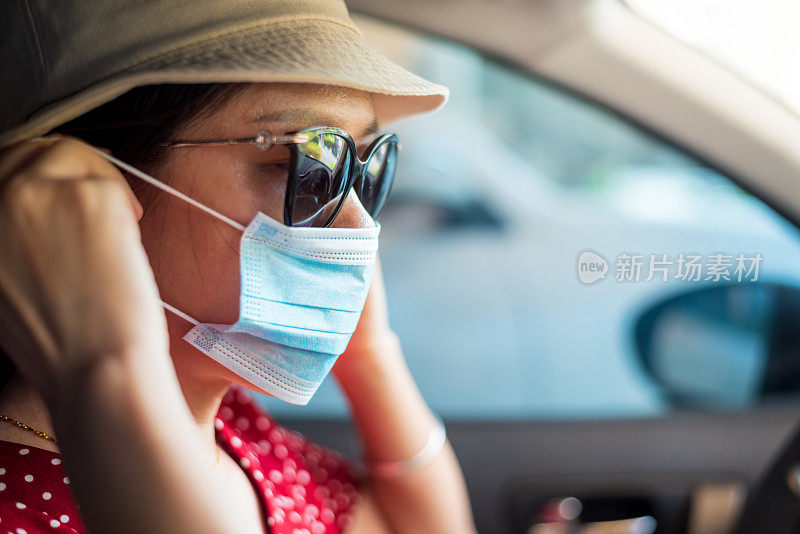 出门前在车里戴着并调整着外科口罩的妇女