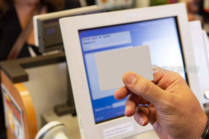 在零售收银台前，一只手拿着空白的身份证或信用卡。