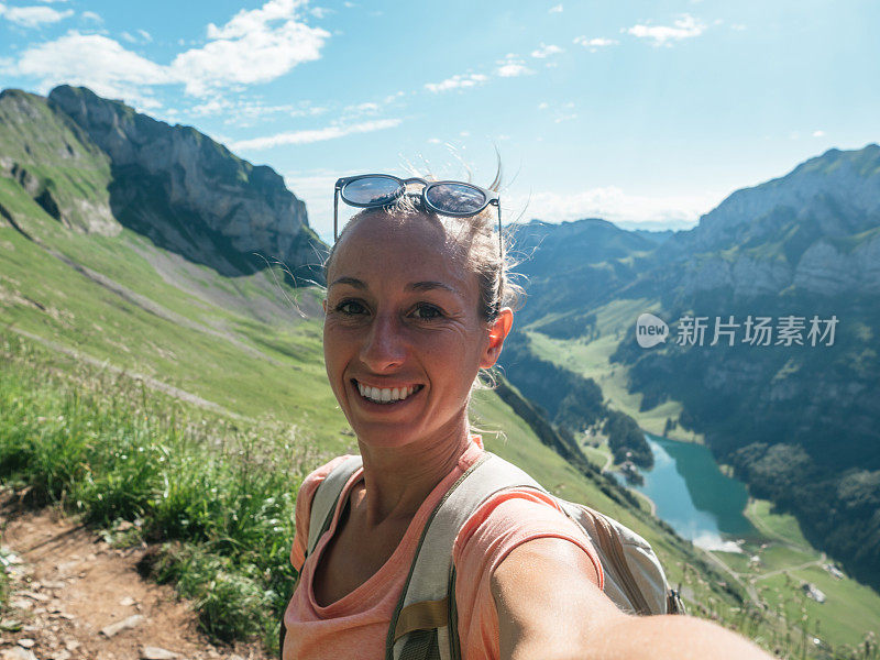 一名女子在瑞士徒步旅行，然后停下来自拍一张全景图