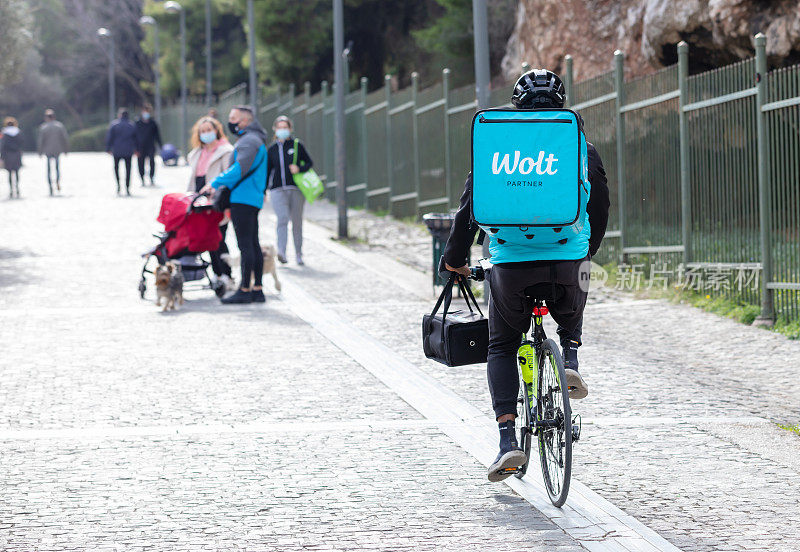 希腊雅典。沃尔特·速递骑着自行车，后视镜。在市中心，Areopagitou街提供食品配送服务