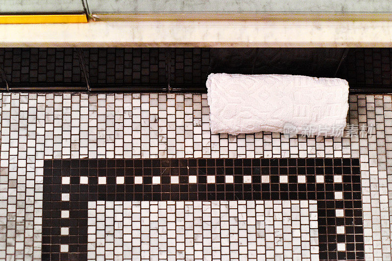 毛巾卷在黑白浴室地砖上