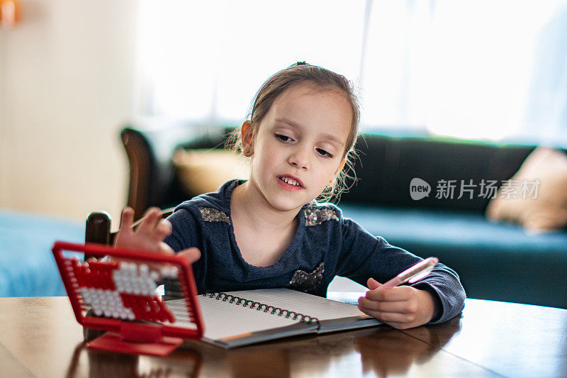 微笑的小女孩在家里计算算盘