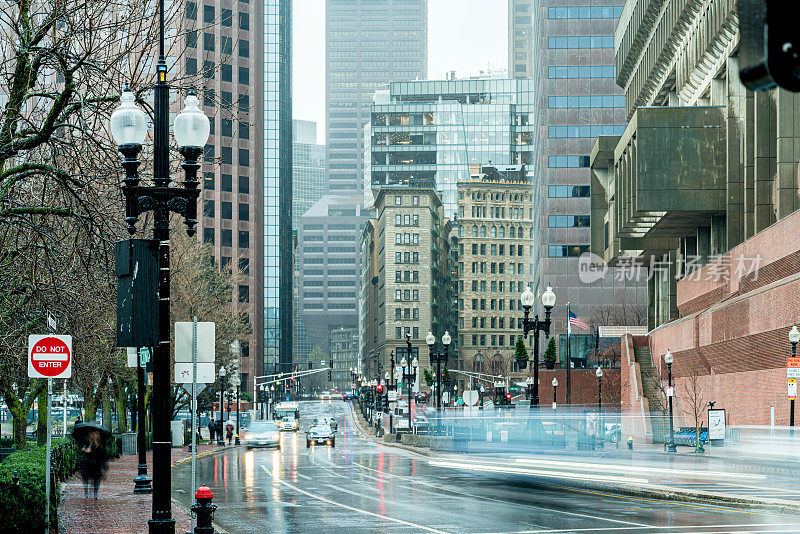 在美国马萨诸塞州波士顿市中心的雨天，人群、行人和交通车辆与高层建筑
