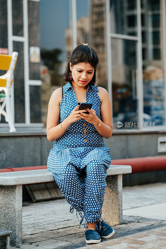 年轻漂亮的女人坐在桌子上用手机。