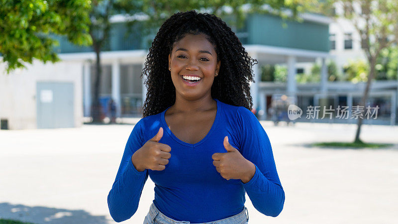 在城市里笑着竖起大拇指的非裔美国年轻女子