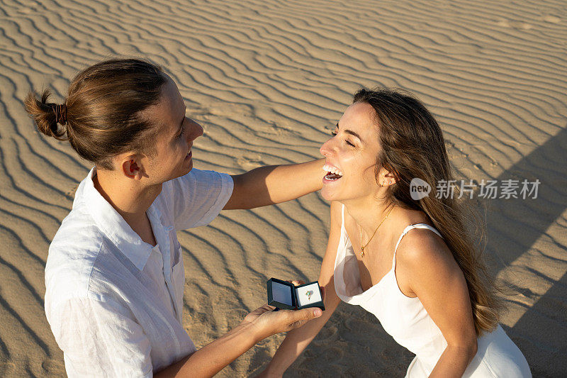 日落时分，一个男人在沙滩上向一个喜出望外的女人求婚