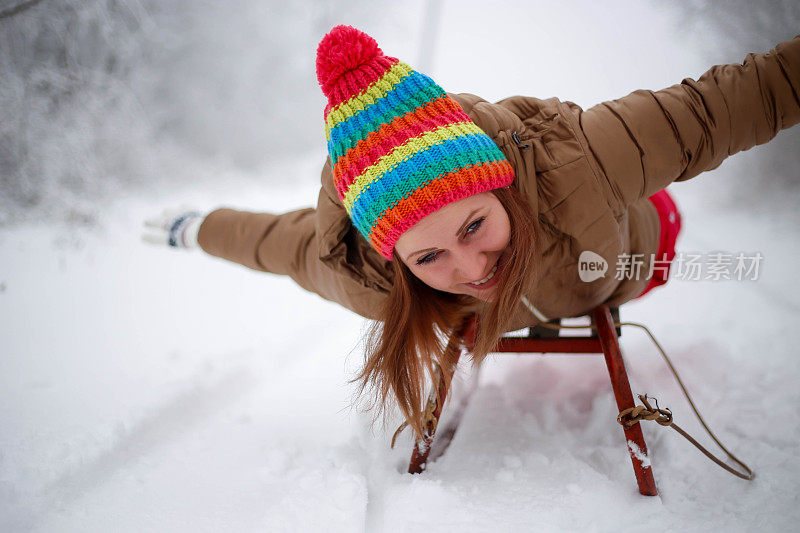 快乐的年轻女子在一个快速的雪橇骑下冰冷的斜坡