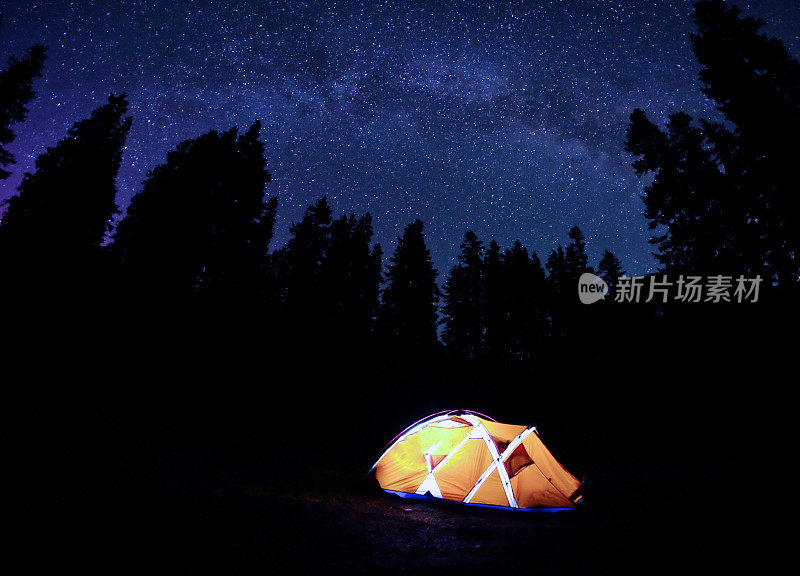 夜间银河下的橙色帐篷。