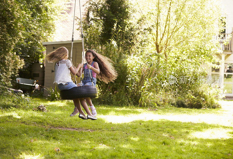 两个女孩在花园里玩秋千