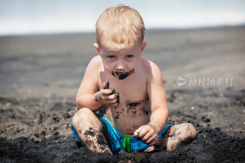 快乐的肮脏的孩子玩沙子在家庭海滩度假