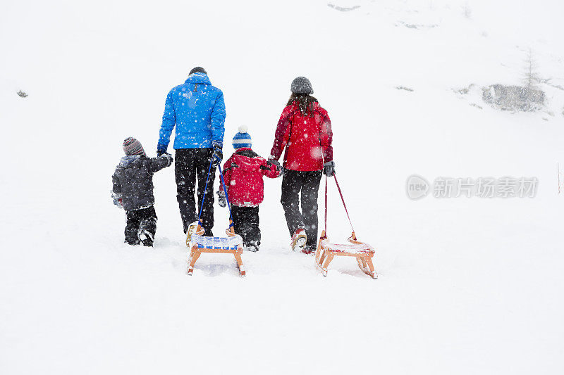 一家人在雪地里拉着雪橇散步