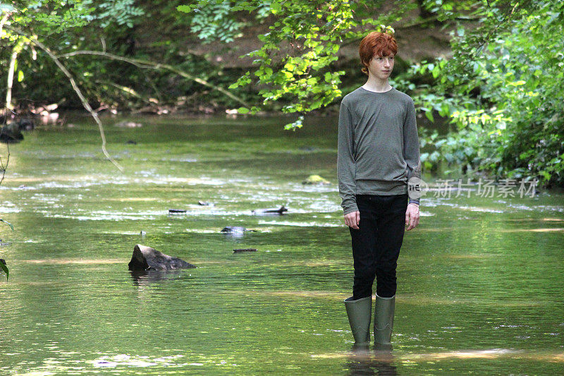 穿着绿色长筒靴的男孩在浅水中涉水