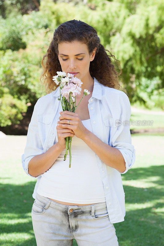 漂亮女人在公园里闻着花香