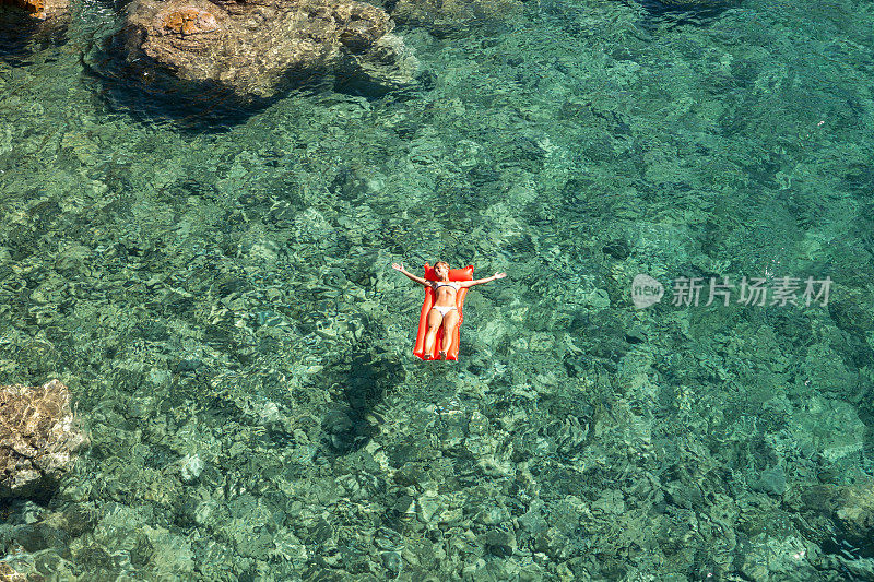 年轻女子浮在泳池床垫上的鸟瞰图