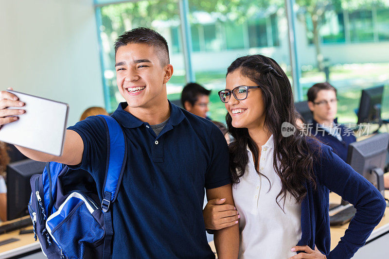 快乐的年轻高中情侣在教室自拍照片