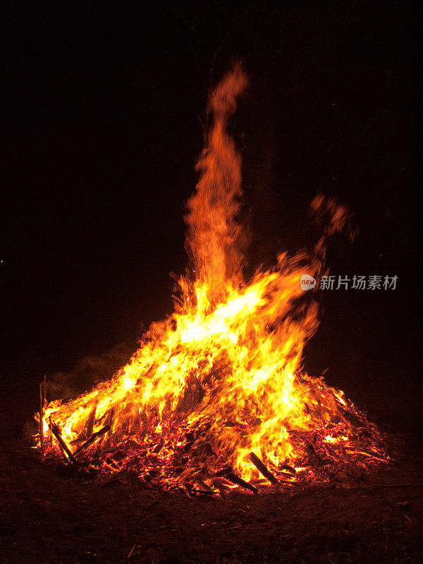 橙色的火焰从一个巨大的户外木柴篝火上蹿起