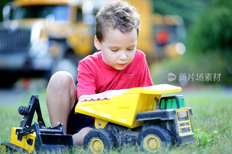 小男孩在自家门前的草坪上玩玩具卡车