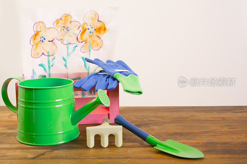 园艺工具。绿色和蓝色的铁锹，手套，喷壶。花。