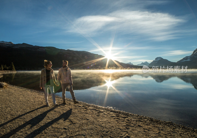 日出时分，一对年轻夫妇在湖边散步