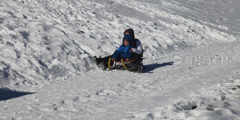 男孩们玩雪橇冬季运动，在瑞士阿尔卑斯山滑雪
