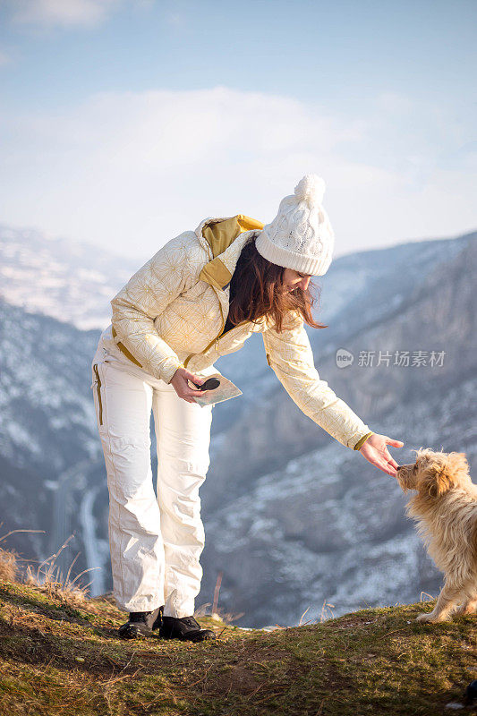 一个女人带着狗在雪地里走在村里的街道上