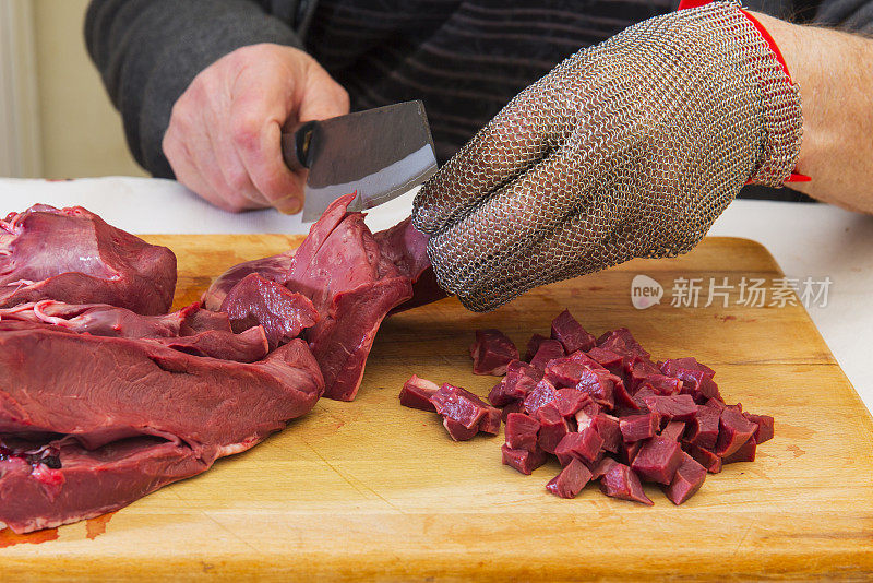 男人切牛肉心，戴着保护性的屠夫手套