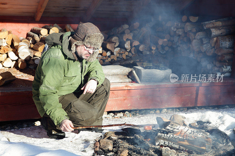 一名男子在户外生火煮香肠