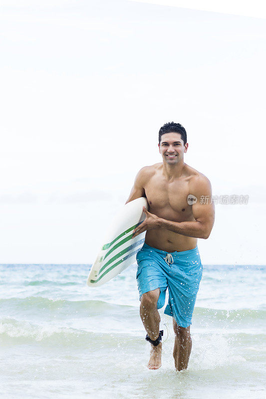 赤裸上身的年轻人在海里拿着冲浪板跑步