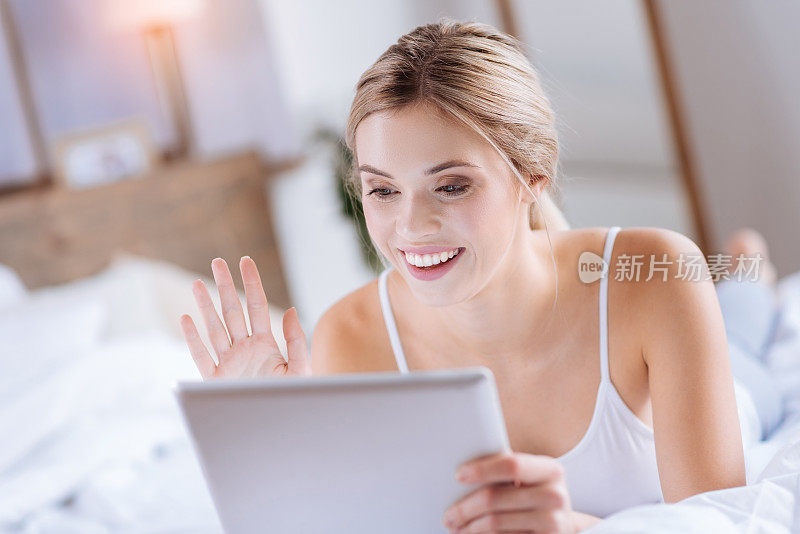 开朗的金发女人正在用平板电脑打视频电话
