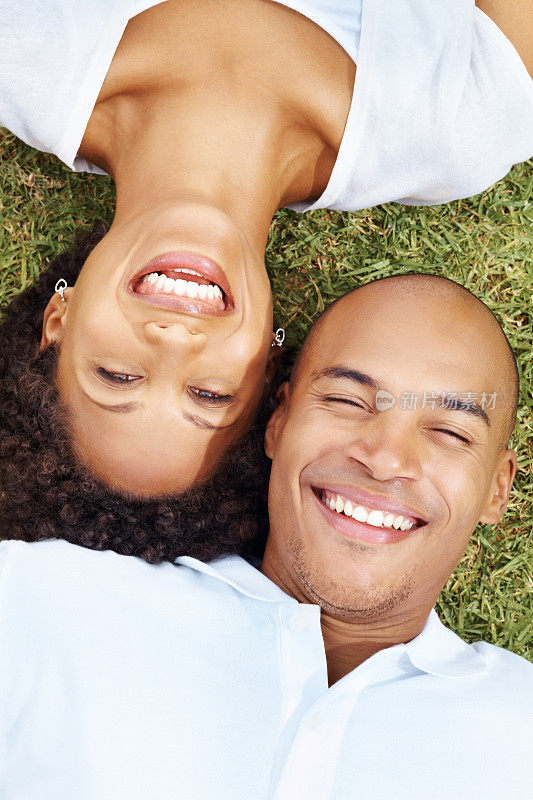 一对美国黑人年轻情侣躺在草地上相爱