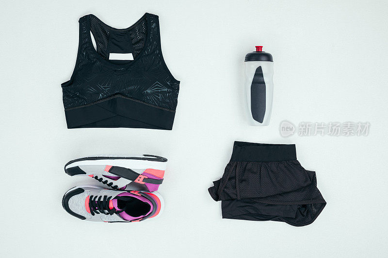 顶视图的运动服与运动鞋和运动瓶孤立的灰色