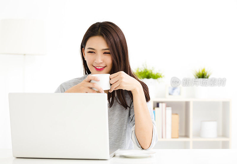 年轻女人在客厅用笔记本电脑工作