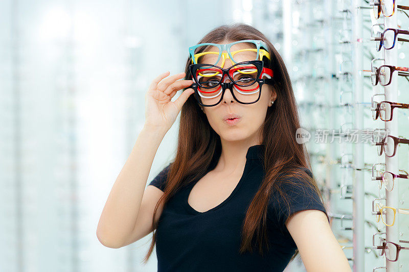 有趣的女人尝试许多眼镜框在眼镜店