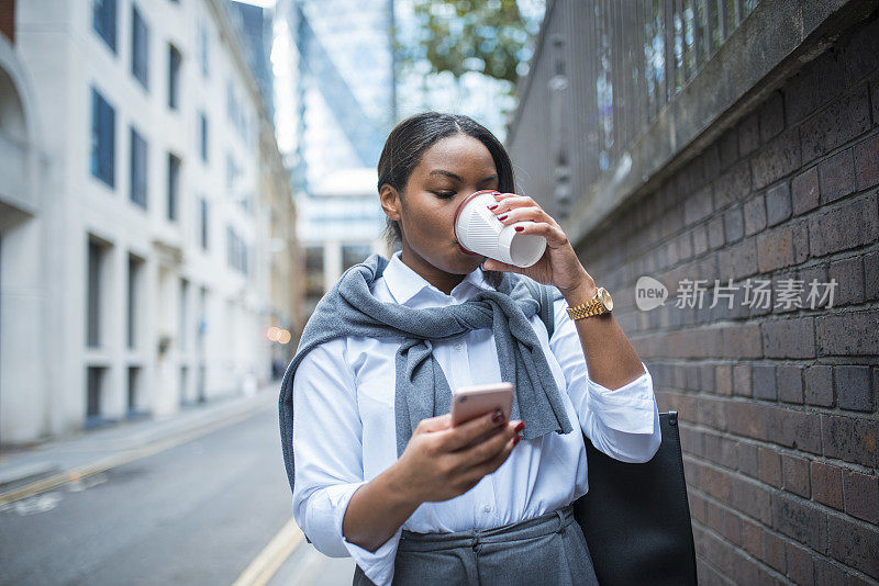 用手机和喝咖啡的女商人。