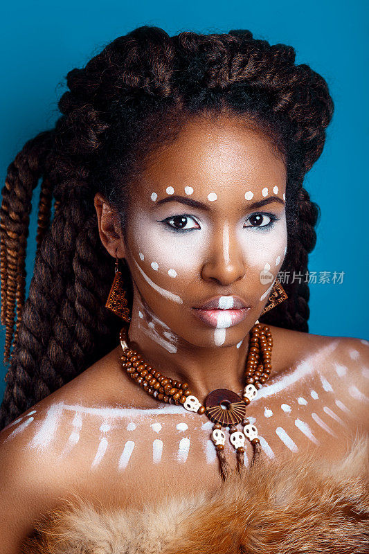 非洲风格的女人。迷人的年轻女子在民族珠宝。一个女人的近距离肖像与一个涂抹的脸。创意的妆容和明亮的风格。