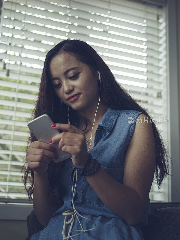 女人坐在沙发的扶手上，听着音乐