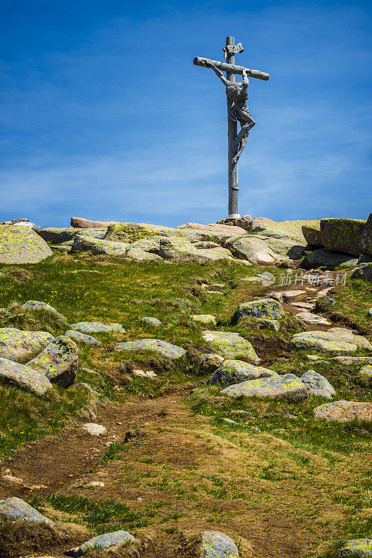 在Dolomites的山顶上有一个木制十字架和被钉上十字架的基督