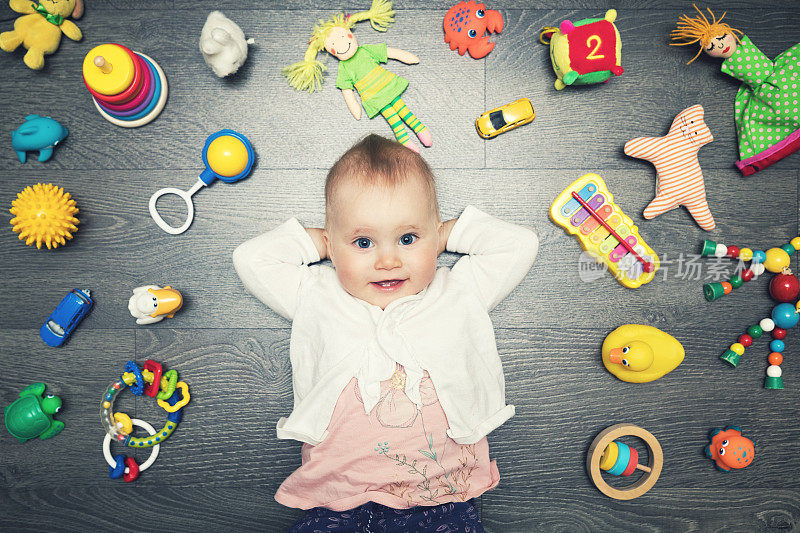 可爱的小女孩和许多玩具在地板上。俯视图
