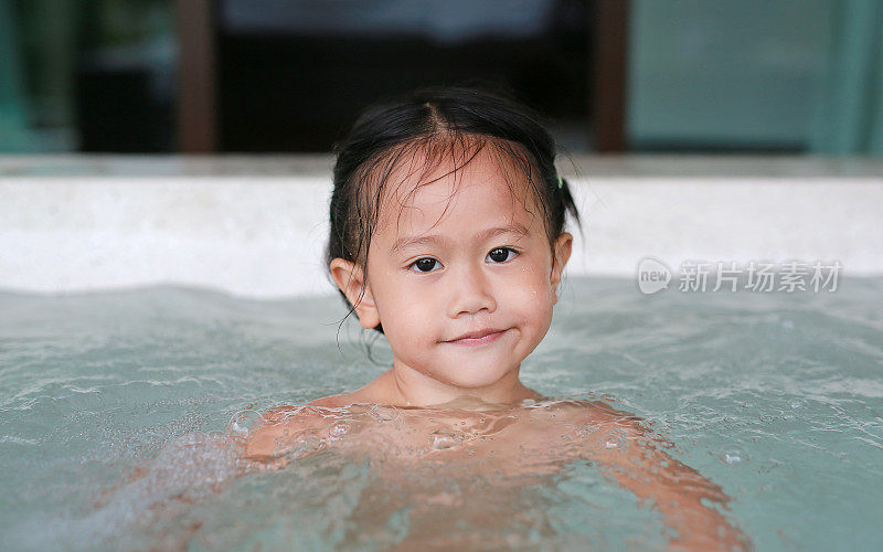 快乐的亚洲小女孩躺在热水浴缸里。